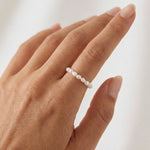 Model wearing a minimalist freshwater pearl ring band on the finger, featuring small natural white pearls arranged in a delicate row. Designed for women seeking a lightweight, elegant pearl ring for everyday wear that offers a refined, comfortable alternative to traditional metal rings.