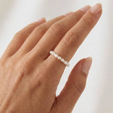 Model wearing a minimalist freshwater pearl ring band on the finger, featuring small natural white pearls arranged in a delicate row. Designed for women seeking a lightweight, elegant pearl ring for everyday wear that offers a refined, comfortable alternative to traditional metal rings.