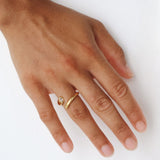 Close-up of a hand wearing the Celine gold open ring with a white cubic zirconia stone on a minimal white background. Designed for women who want an elegant everyday ring, this stainless steel ring with 18k gold PVD adds subtle sparkle and helps elevate simple outfits with minimal effort.