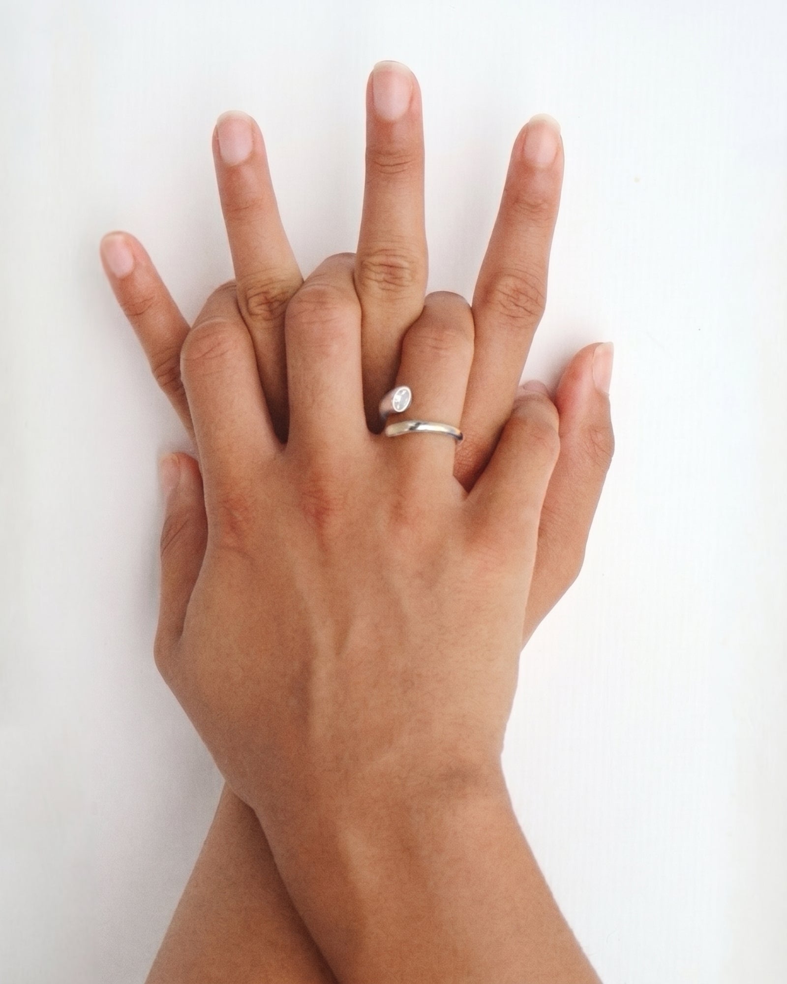 Close-up of a hand wearing the Celine silver open ring with a white cubic zirconia stone against a clean white background. Perfect for women who prefer minimal silver jewellery, this stainless steel ring adds a soft sparkle and helps create an effortless everyday ring stack.