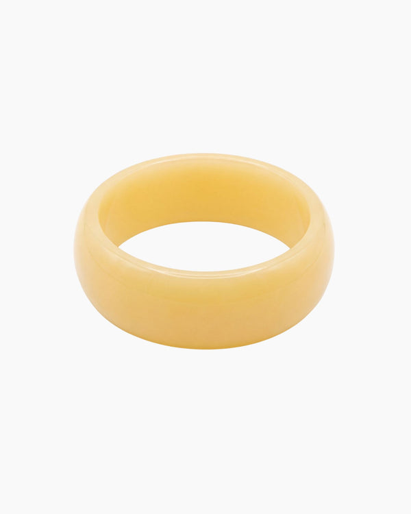 Chunky butter yellow resin bangle with a glossy polished finish. The Lumi Resin Bangle is a modern statement bracelet designed for effortless everyday styling, capsule wardrobes, minimal fashion, and elevated neutral outfits.