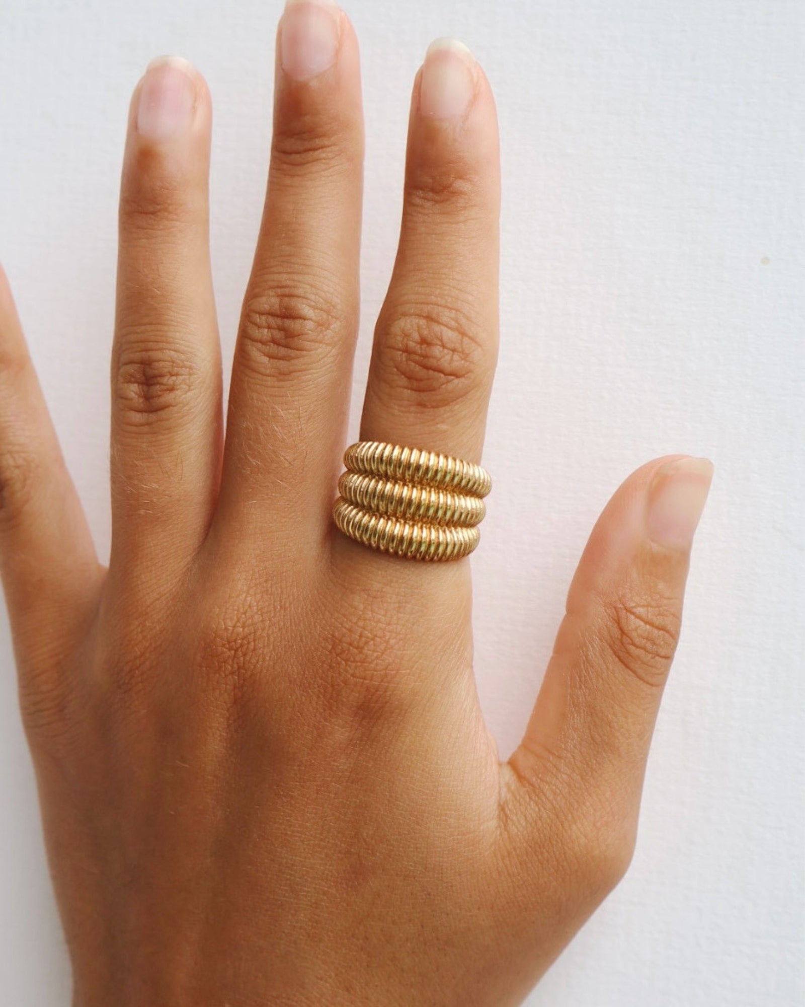 Dara gold ribbed statement ring worn on the finger, showing the chunky layered design for customers wanting a comfortable stainless steel statement ring for everyday styling and jewellery stacking.