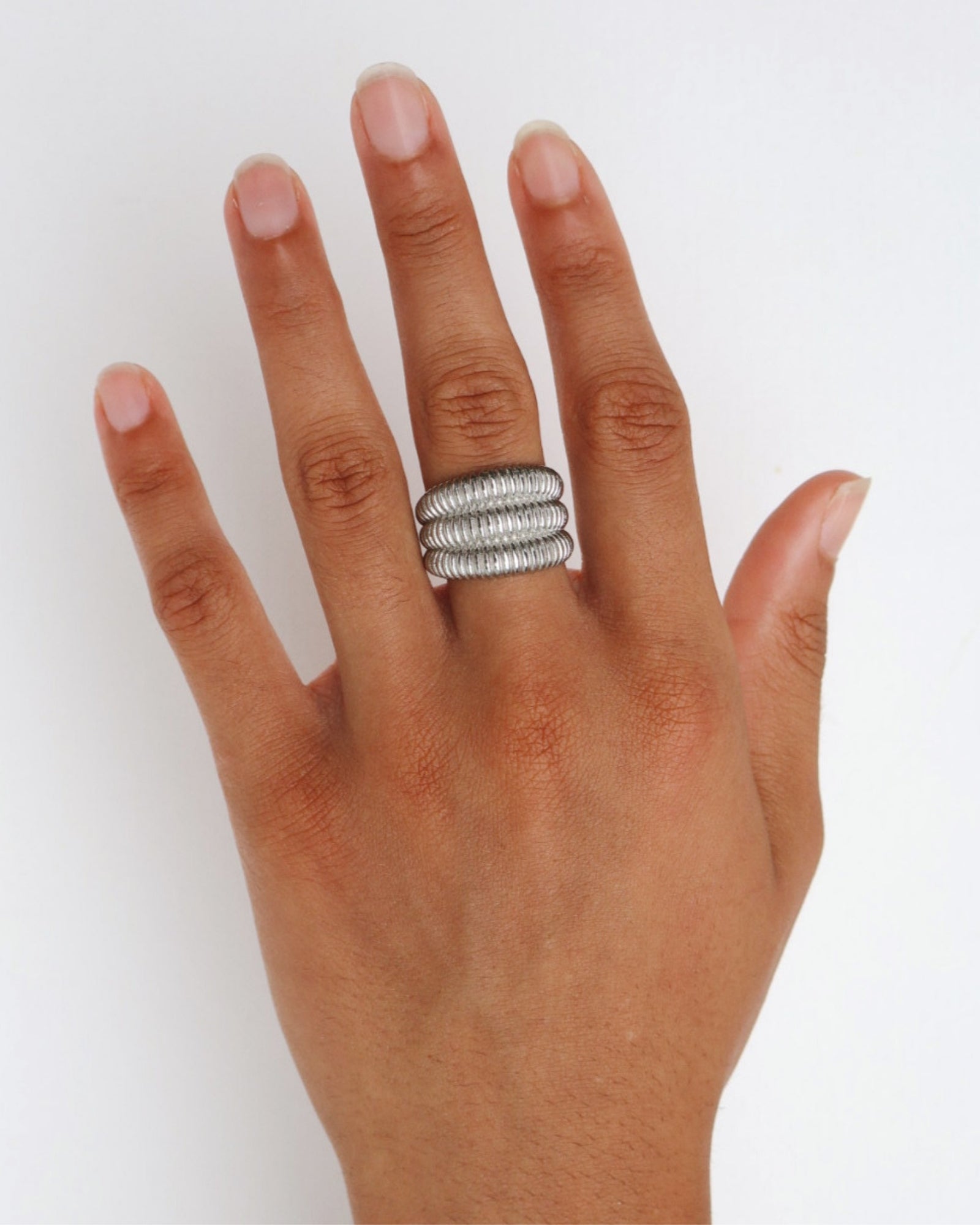Dara silver ribbed statement ring worn on the finger, showing the wide sculptural shape for shoppers looking for a durable stainless steel ring that is easy to style day or night.