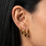 Model wearing SELENE rounded gold hoop earrings in small, medium and large sizes. Polished sterling silver hoops with micron 18k gold plating styled as a layered ear stack for timeless everyday jewellery looks and elevated minimal styling.
