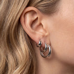 Model wearing SELENE rounded silver hoop earrings in small, medium and large sizes. Polished sterling silver hoops with rhodium plating styled as a layered ear stack for timeless everyday jewellery, minimalist styling and comfortable wear for sensitive ears.