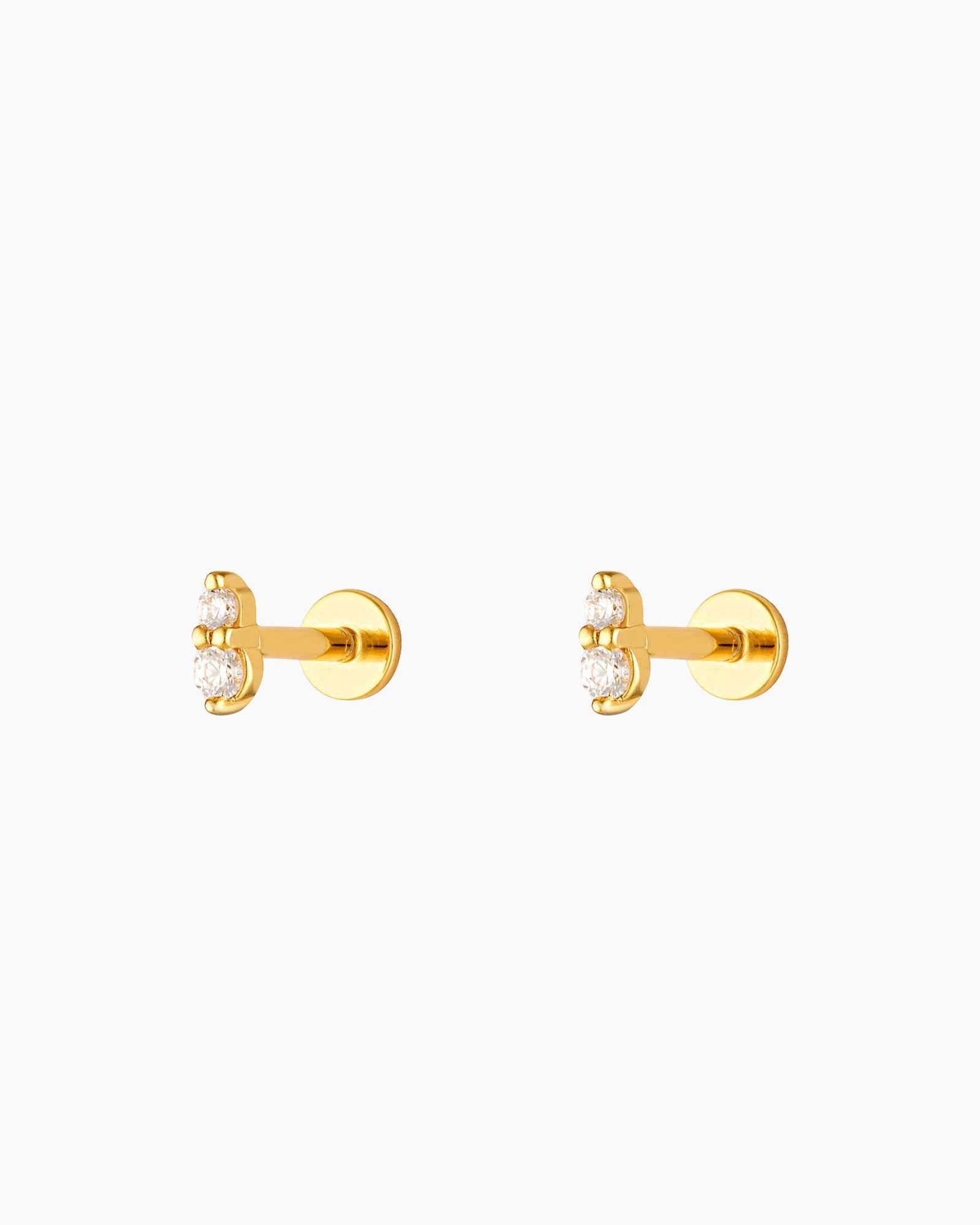 A pair of gold-colored earrings with white crystal studs, displayed against a white background.
