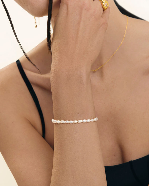 Model wearing a minimalist freshwater pearl bracelet on the wrist, styled with a black outfit and gold jewellery. Designed for women seeking an elegant everyday pearl bracelet that complements casual, office, and elevated looks while offering a lightweight, comfortable, and refined jewellery option.