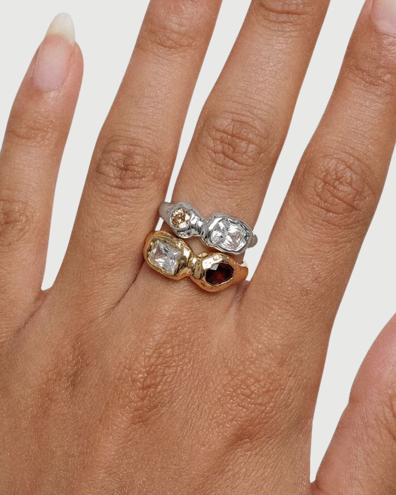 Close-up of silver and gold sculptural gemstone rings worn together, highlighting the contrast between metals, stone colours, and organic settings. Designed to assist customers in choosing between gold or silver and understanding how the rings layer for a bold yet cohesive look.