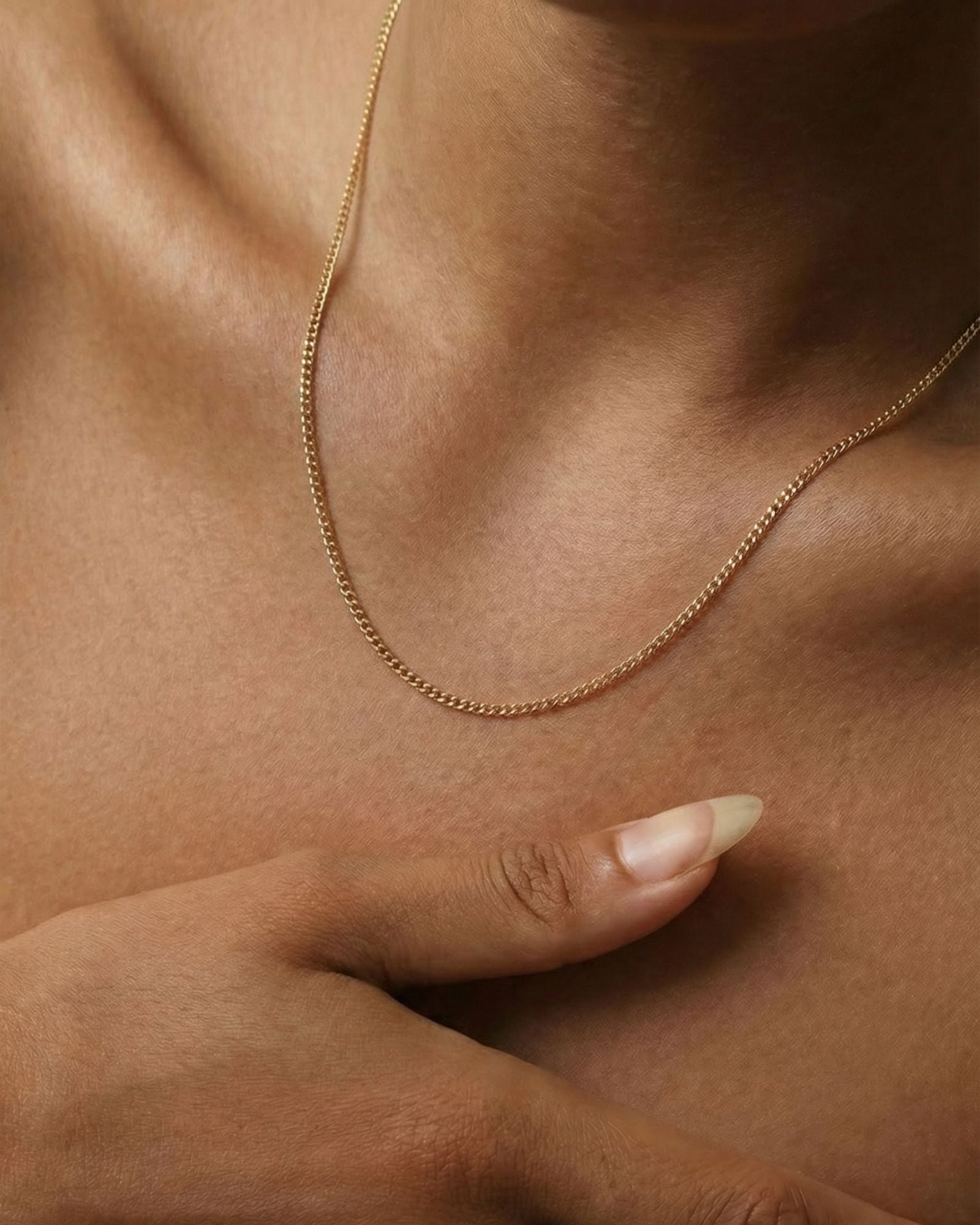 Close-up of a model wearing the Arlo gold filled curb chain necklace, a delicate everyday chain styled alone on the collarbone for a minimal layered jewellery look.