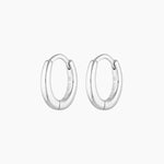Pair of polished silver oval huggie hoop earrings shown on a clean white background, featuring a smooth, rounded silhouette and a secure hinged clasp with a 925 sterling silver stamp. Designed for women seeking minimalist silver hoop earrings for everyday wear, these lightweight huggie hoops suit sensitive ears and offer a comfortable, tarnish-resistant option for daily styling, stacking with other earrings, or wearing alone for a clean, modern look.