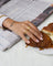 Product image of a woman’s hand wearing stacked gold rings, including an organic spiral gold ring and a slim textured band, resting beside a croissant on a plate and a newspaper. Designed for women seeking everyday gold jewellery, this image shows how minimalist gold rings can be styled effortlessly for daily routines, offering a versatile and understated option for casual, refined wear.