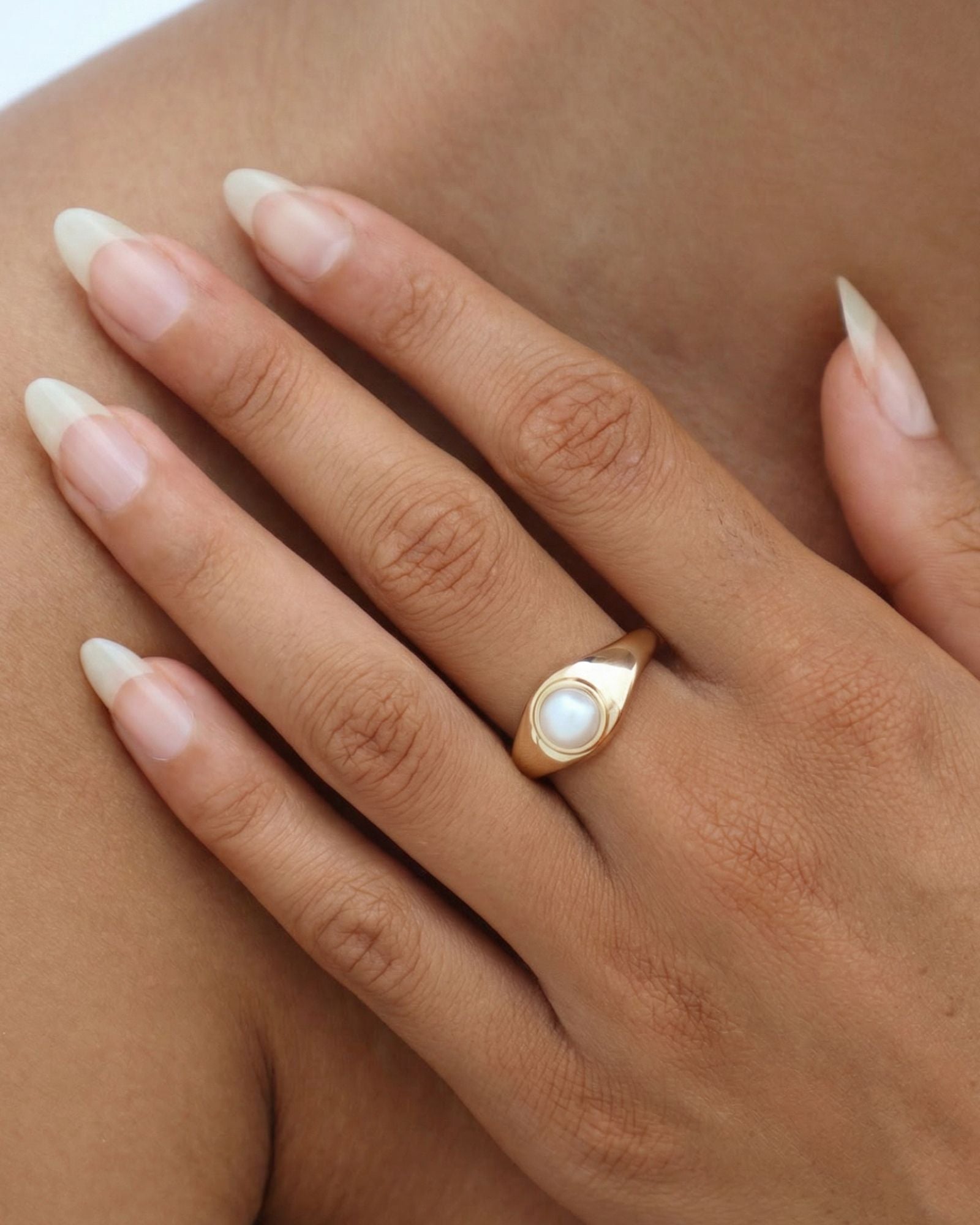 14k solid gold pearl signet ring worn on hand, featuring a low-set freshwater pearl in a smooth, sculpted band designed for everyday wear.