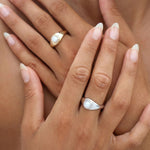 Gold and silver pearl signet rings worn on hand, featuring low-set freshwater pearls and sculpted bands designed for modern everyday jewellery.