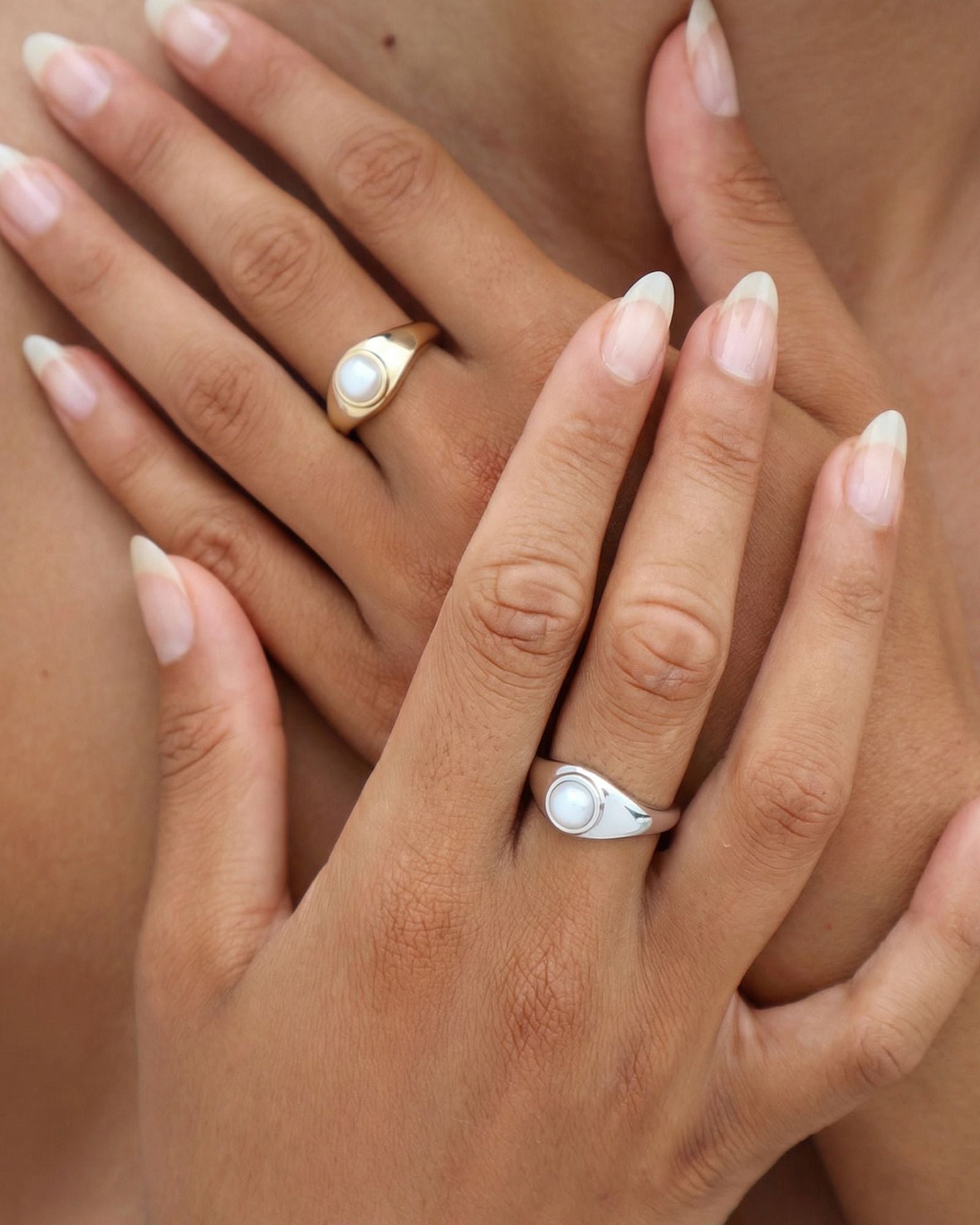 Gold and silver pearl signet rings worn on hand, featuring low-set freshwater pearls and sculpted bands designed for modern everyday jewellery.