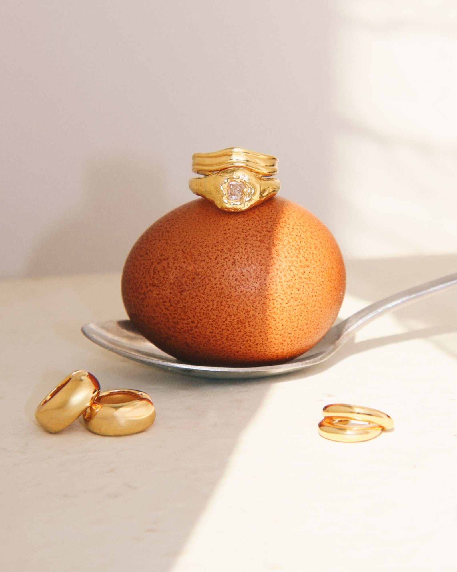 Gold rings on a brown egg,  gold statment hoops and a double ear cuff 