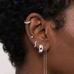 Close-up of a woman’s ear wearing silver Eva hoop earrings paired with silver studs and a chain drop earring. For women looking for modern silver earring layering ideas and balanced ear stacks.