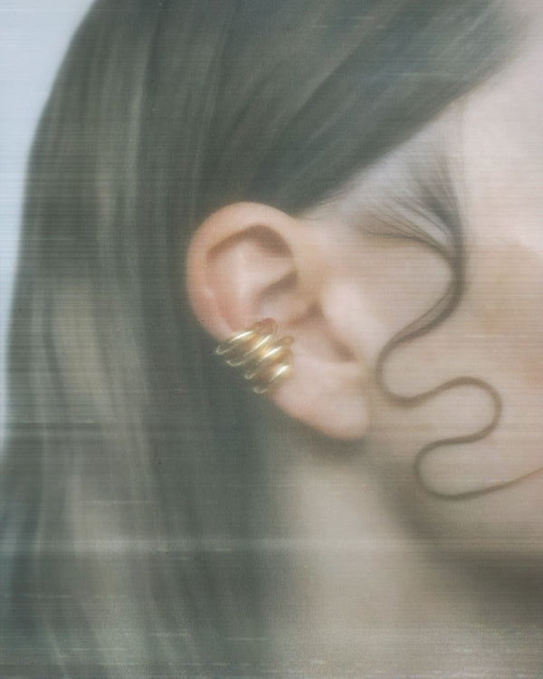 Gold Flux Ear Cuff styled on the ear, showing its double band no piercing design with soft hair framing the ear; minimalist jewellery look for everyday wear.