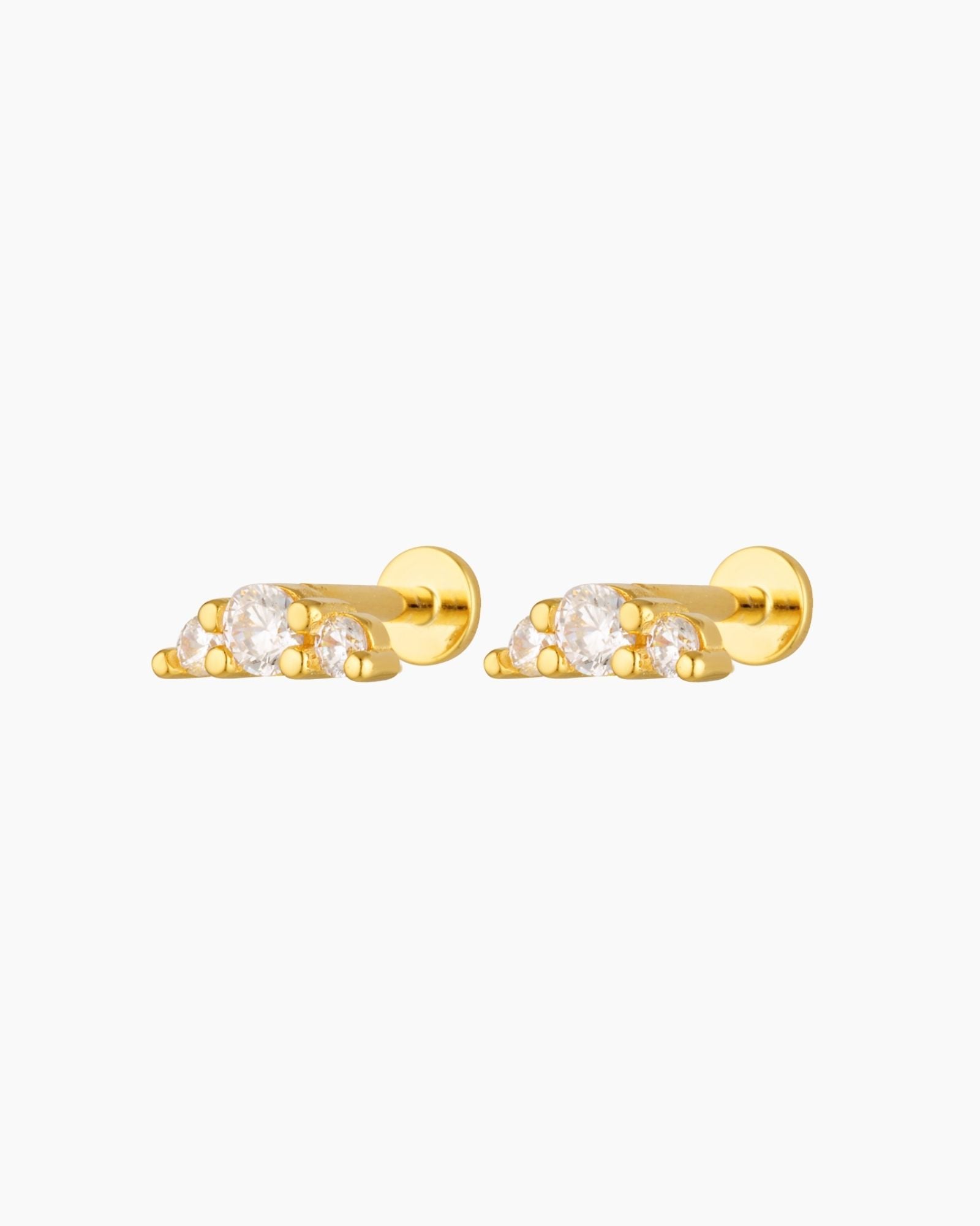 Pair of gold flat back stud earrings featuring three round cubic zirconia stones in a minimalist cluster design, shown on a white background. Designed for people with cartilage, helix or lobe piercings who want comfortable, hypoallergenic flat back earrings that sit flush to the ear and are suitable for everyday wear, sleeping, and sensitive ears.