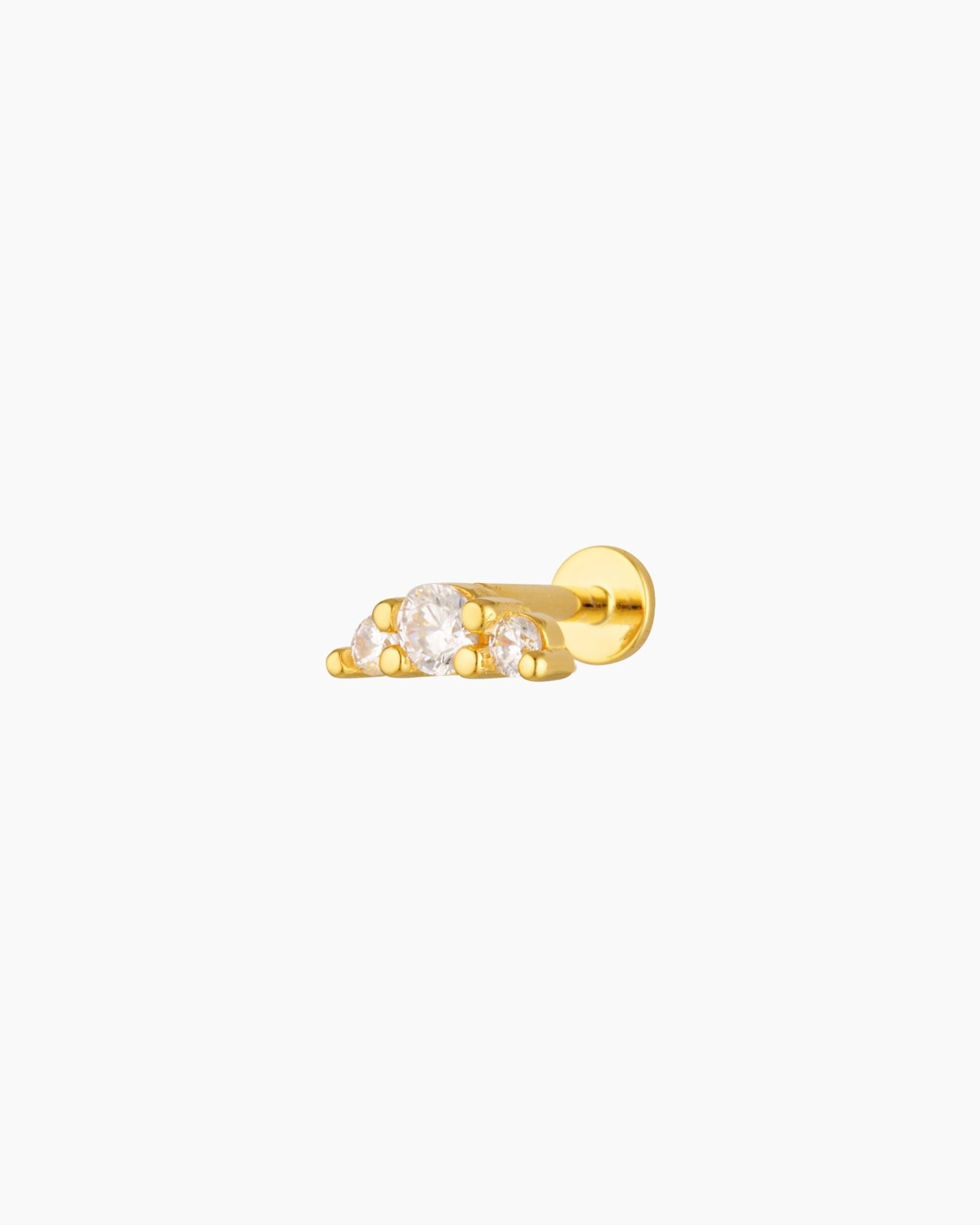 Studio product image of a single gold flat back stud earring featuring three cubic zirconia stones in a minimalist setting. Designed for cartilage, helix, and lobe piercings, this flat back earring offers a low-profile, comfortable fit ideal for sensitive ears, sleeping, and everyday wear while adding subtle sparkle to a curated ear stack.