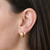 Close-up side profile of a brunette woman’s ear styled with gold jewellery, featuring stacked gold hoops, a pavé huggie earring, and a small gold star stud. Created for women who want refined gold earrings for daily wear, this image shows size, placement, and layering options to help customers choose gold hoops and huggies that work together without looking heavy or overcrowded.