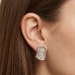Close-up side profile of a woman’s ear wearing a silver statement stud earring with an organic, sculptural rectangular shape and textured surface. Designed for women who want bold yet refined silver jewellery, this image helps customers understand the size, shape, and fit of the silver stud earring for everyday wear or minimalist statement styling.