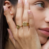 Product image of a woman’s face and hand wearing stacked gold rings, including an organic spiral gold ring and a textured gold band, shown near the ear. Designed for women seeking minimalist gold jewellery for everyday wear, this image demonstrates how stacking gold rings creates a refined, cohesive look while offering versatile styling for daily and elevated outfits.