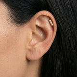 Close-up of a gold flat back cartilage stud featuring three petite freshwater pearls set in a vertical row, worn in the upper ear helix. Designed for women seeking comfortable flat back ear piercings for sensitive ears, this minimalist pearl stud offers a secure, low-profile option for healed or new cartilage piercings, suitable for everyday wear, bridal styling, and all-day comfort.