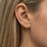 Close-up of a woman’s ear styled with a minimalist gold ear stack, featuring a dainty flower stud earring in the lobe, a small gold hoop, a delicate gold chain drop earring, and a tiny crystal flat-back stud in the upper cartilage. Designed for women seeking refined, everyday earrings for lobe and cartilage piercings, this image highlights comfortable, lightweight jewellery ideal for sensitive ears and effortless ear stacking.