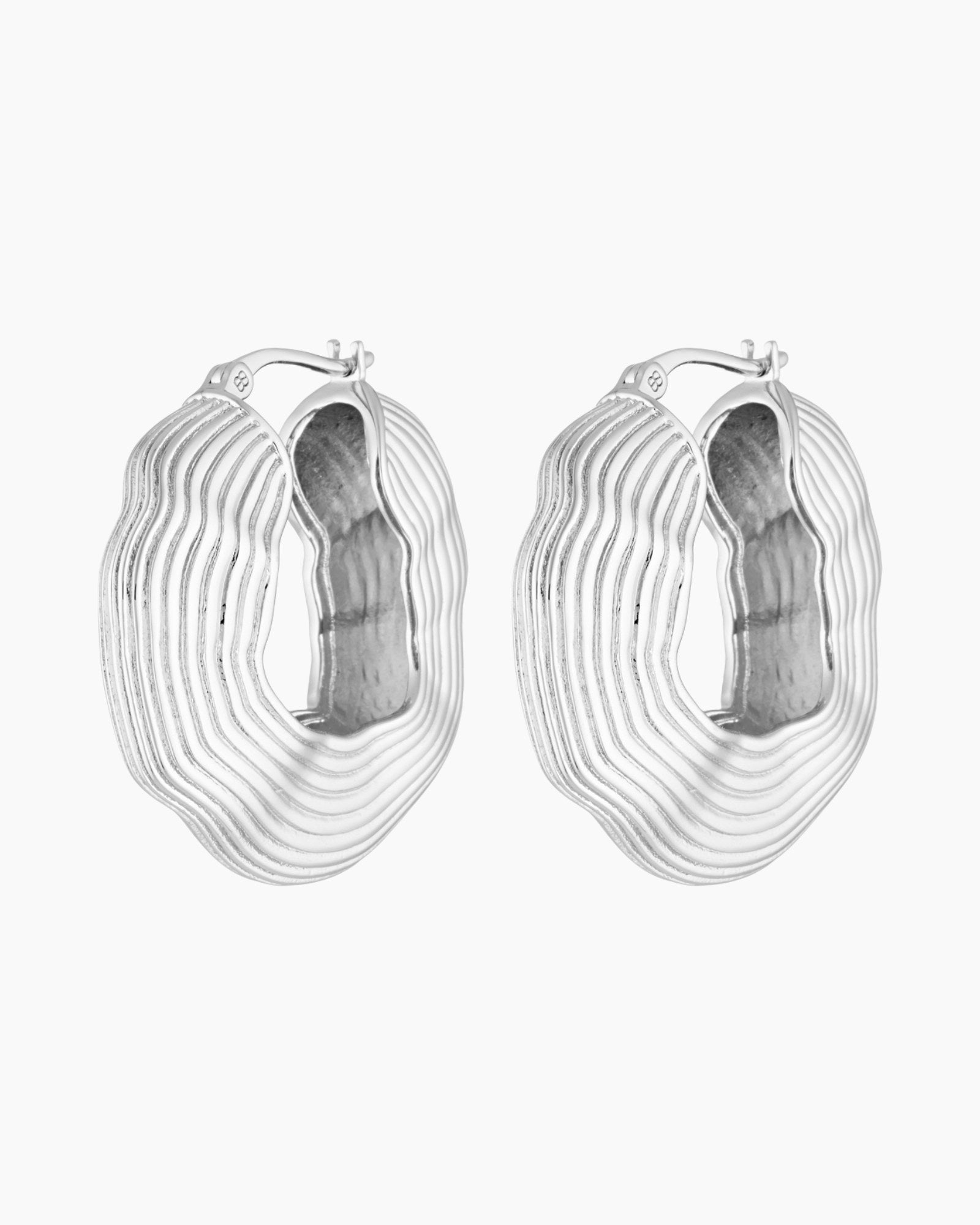 Silver statement hoop earrings with bold sculptural layered texture, rhodium plated design photographed on a white background.