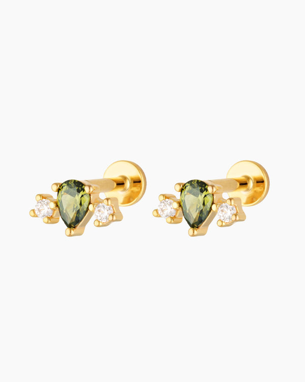 Pair of gold flat back cartilage studs featuring a green pear-cut gemstone with two cubic zirconia accents, 18k gold plated sterling silver, on a white background.