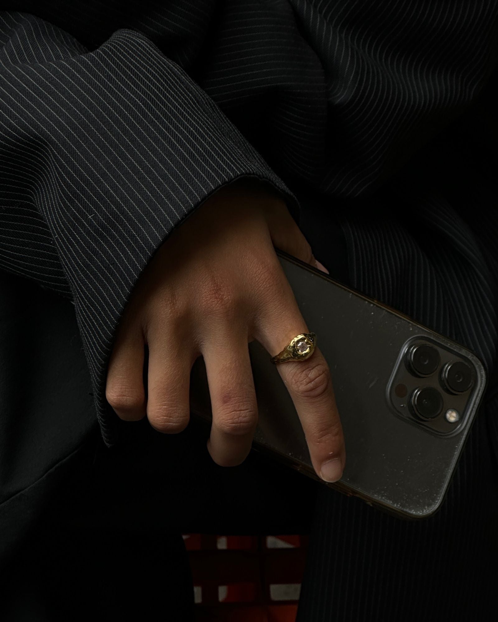 dark aesthetic photo of a gold filled ring ith white gemstone 