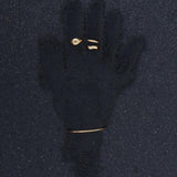 Flat lay of minimalist gold jewellery arranged on dark textured sand, featuring a slim gold bangle bracelet, a delicate gold ring with a clear stone, and two small gold bands. Designed for women who prefer understated, everyday gold jewellery, this image highlights a cohesive, minimalist jewellery set ideal for layering and stacking. The photo helps customers visualise how simple gold bangles and rings can be styled together for a refined, modern look with low-maintenance elegance.