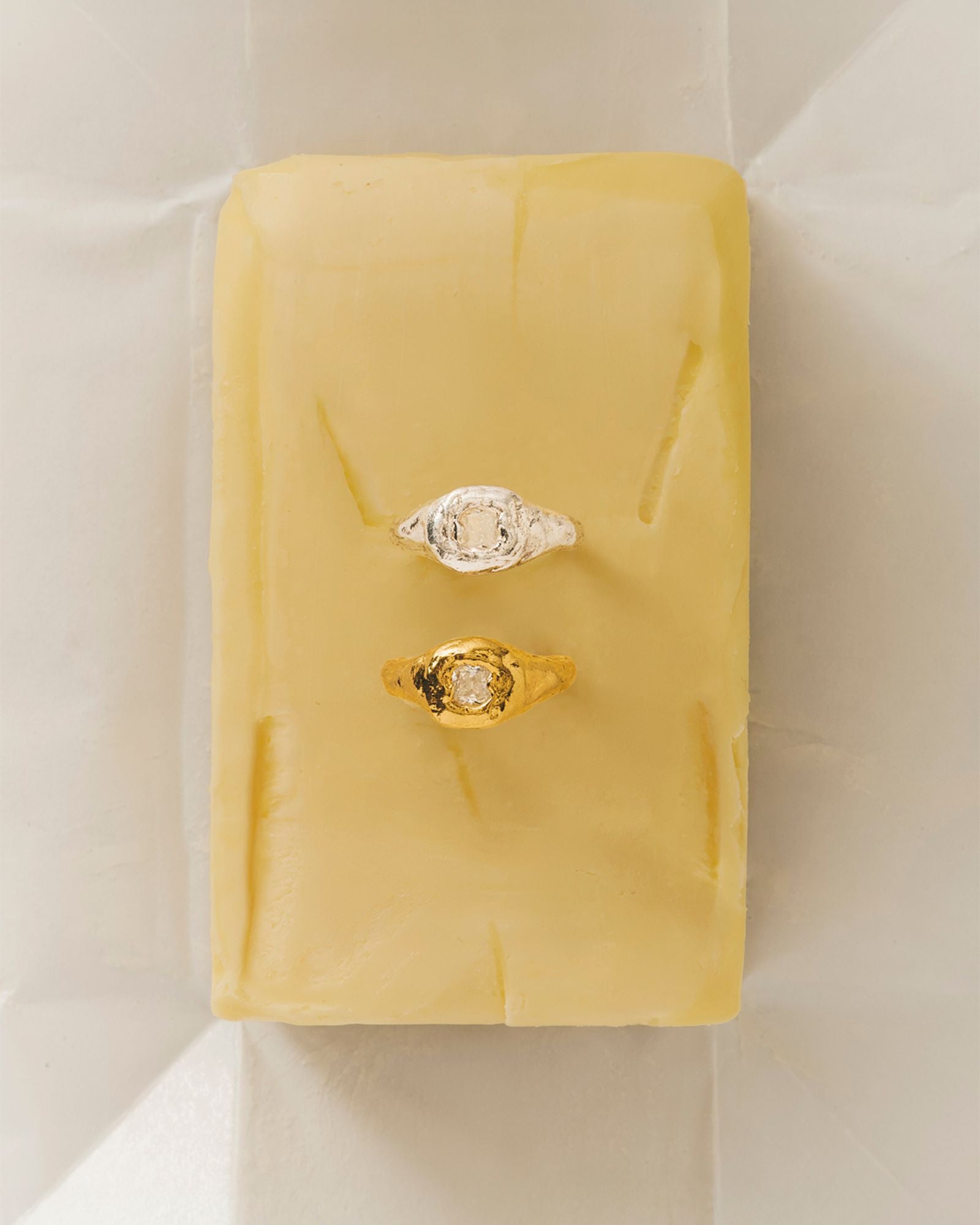 handmade organic textured gold filled ring and one organic shaped ring in silver with white gemstone on a butter stick