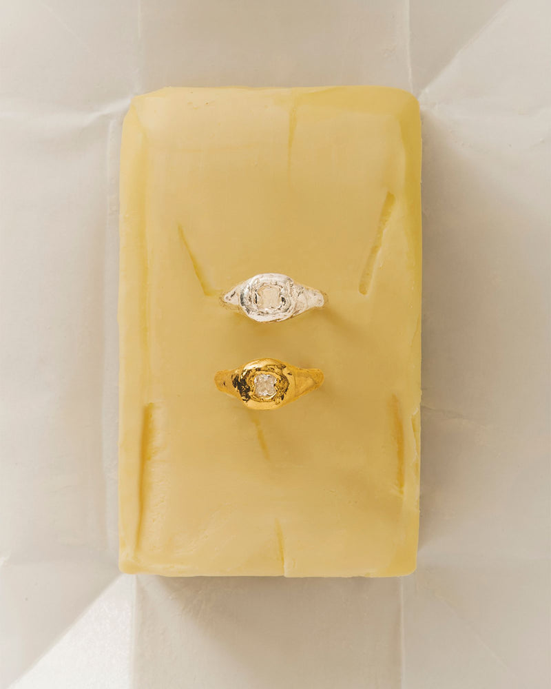 handmade organic textured gold filled ring and one organic shaped ring in silver with white gemstone on a butter stick