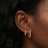 Close-up side profile of a woman’s ear wearing two small gold hoop earrings, including a twisted rope-style gold hoop and a smooth, ridged gold huggie. Designed for women who want classic gold hoop earrings for everyday wear, this image helps customers see the size, texture, and fit of layered gold hoops on the ear, making it easier to choose between subtle and statement hoop styles.