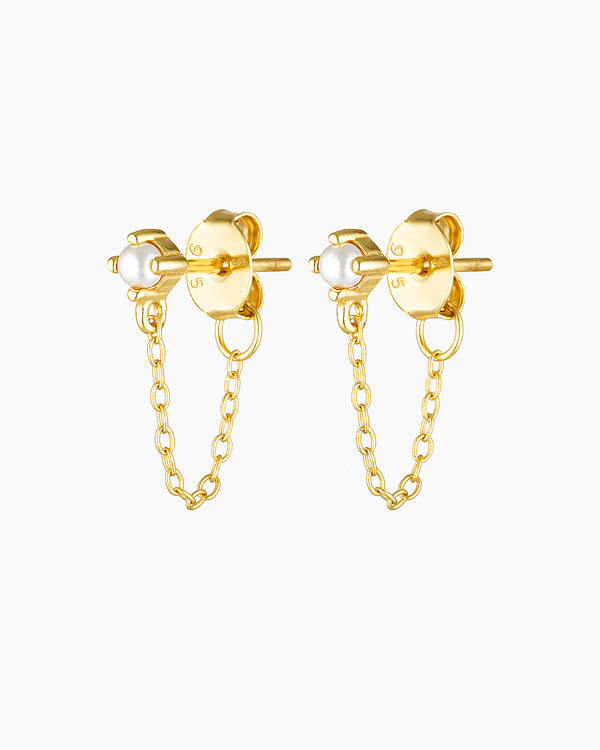 Studio product image of the Assana pearl stud earrings in gold, featuring small white pearl studs set on a solid sterling silver base with long-lasting 18k micron gold plating and a delicate gold chain connecting the stud to the butterfly backing. Designed for adults seeking minimalist pearl earrings, chain stud earrings, or hypoallergenic gold jewellery for sensitive ears, these earrings offer a secure, lightweight option that adds subtle movement and elegance to everyday wear, layered ear stacks, and refi
