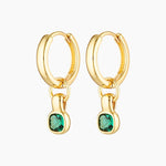 Pair of small gold hoop earrings with removable emerald green cubic zirconia charm, photographed on a white background. The earrings feature polished 18K gold-plated hoops with a dangling rectangular emerald-style stone. Designed for women seeking versatile everyday gold hoop earrings that add subtle colour, movement, and refined birthstone detail while remaining lightweight and wearable for daily styling.
