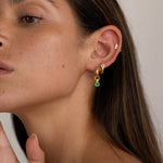 Alt text:

Close-up side profile of a woman wearing a layered gold ear stack featuring a flat back cartilage stud with small cubic zirconia stones, a gold huggie in the lobe, and a gold hoop with a green gemstone drop. The image shows how flat back earrings and cartilage studs can be styled for a modern, elegant ear stack, ideal for people seeking comfortable, secure jewellery for sensitive ears and everyday wear.
