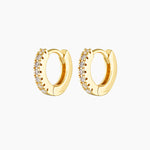 Pair of small gold huggie hoop earrings with a click-lock closure, set with clear cubic zirconia stones along the front, photographed on a white background. Designed for women seeking dainty gold hoop earrings, secure everyday huggies, and stackable earrings for second or third lobe, helix, or cartilage piercings, offering subtle sparkle without bulk or discomfort.
