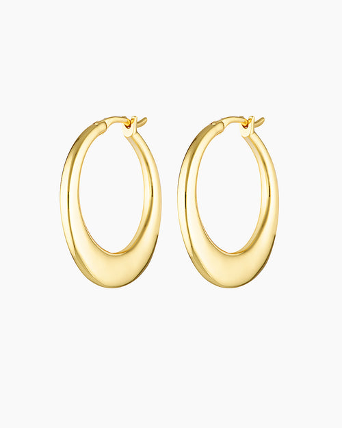 Product photo of a pair of medium-sized gold hoop earrings with a softly sculpted, rounded silhouette and polished finish, shown on a clean white background. The earrings feature a smooth hinged closure and a warm gold tone, highlighting their refined shape and subtle thickness. Designed for women seeking elegant gold hoop earrings that make an impact without feeling heavy, this image showcases statement hoops suitable for occasions, elevated everyday wear, and sensitive ears. Ideal for customers looking fo