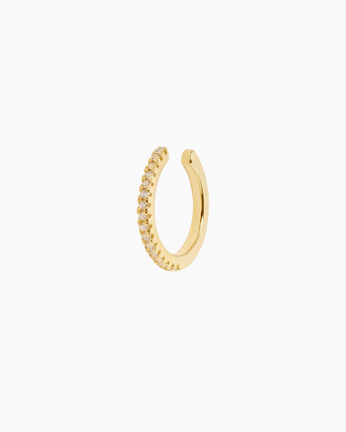 Single gold ear cuff featuring a slim open-band design with a row of small clear gemstones set along one side, photographed on a white background. This no-piercing ear cuff is designed for people who want to elevate their ear stack without committing to additional piercings, offering a minimalist yet refined gold jewellery option that adds subtle sparkle and dimension to everyday or curated ear styling.