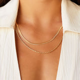 Layered gold necklaces worn on the neck, featuring a slim flat gold chain paired with a delicate gold rope chain, styled on skin with an open white shirt. This image is for women looking for everyday gold necklaces that layer cleanly without tangling and sit comfortably at the collarbone. It helps show necklace length, thickness contrast, and how minimalist gold chains create an elevated, effortless look suitable for daily wear and capsule wardrobes.