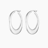 Product photo of a pair of medium-sized silver hoop earrings with a softly sculpted, rounded silhouette and high-polish finish, displayed on a clean white background. The hoops feature a smooth hinged closure and a refined, minimalist shape that reflects light evenly, highlighting their modern design. Designed for women seeking elegant silver hoop earrings that feel elevated yet wearable, this image showcases statement hoops suitable for everyday wear, special occasions, and sensitive ears. Ideal for custom