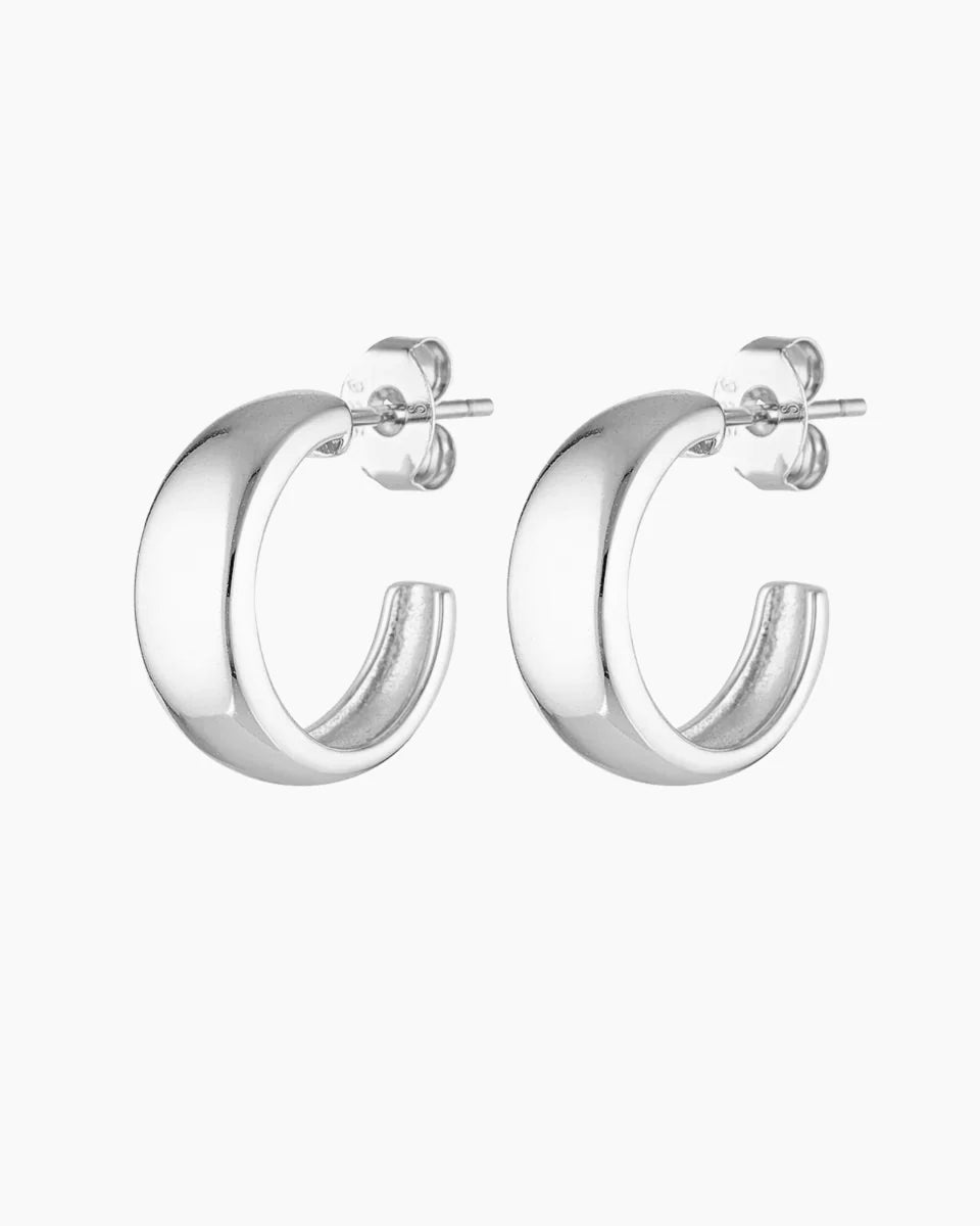 Studio product image of a pair of silver hoop earrings with a smooth, chunky curved silhouette and polished finish, shown front-facing on a white background with secure post and butterfly backs visible. Designed for women seeking small silver hoop earrings, minimalist statement hoops, or hypoallergenic sterling silver earrings for sensitive ears, this image highlights a clean, modern hoop that solves the need for an elevated everyday earring that is versatile, comfortable, and easy to style from day to nigh