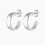 Studio product image of a pair of silver hoop earrings with a smooth, chunky curved silhouette and polished finish, shown front-facing on a white background with secure post and butterfly backs visible. Designed for women seeking small silver hoop earrings, minimalist statement hoops, or hypoallergenic sterling silver earrings for sensitive ears, this image highlights a clean, modern hoop that solves the need for an elevated everyday earring that is versatile, comfortable, and easy to style from day to nigh